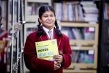 A student with a book near the library shelves at Geeta Jyoti School